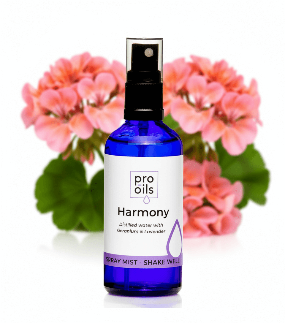Bottle of Pro Oils Harmony spray mist with pink flowers in the background