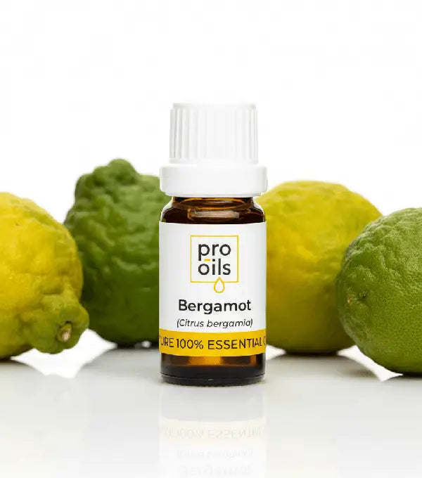 Bottle of Pro Oils Bergamot essential oil with bergamot fruits on a white background