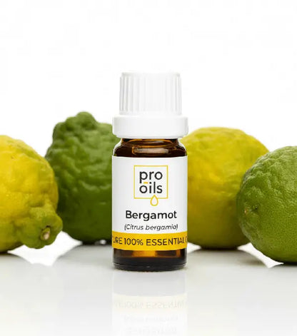 Bottle of Pro Oils Bergamot essential oil with bergamot fruits on a white background